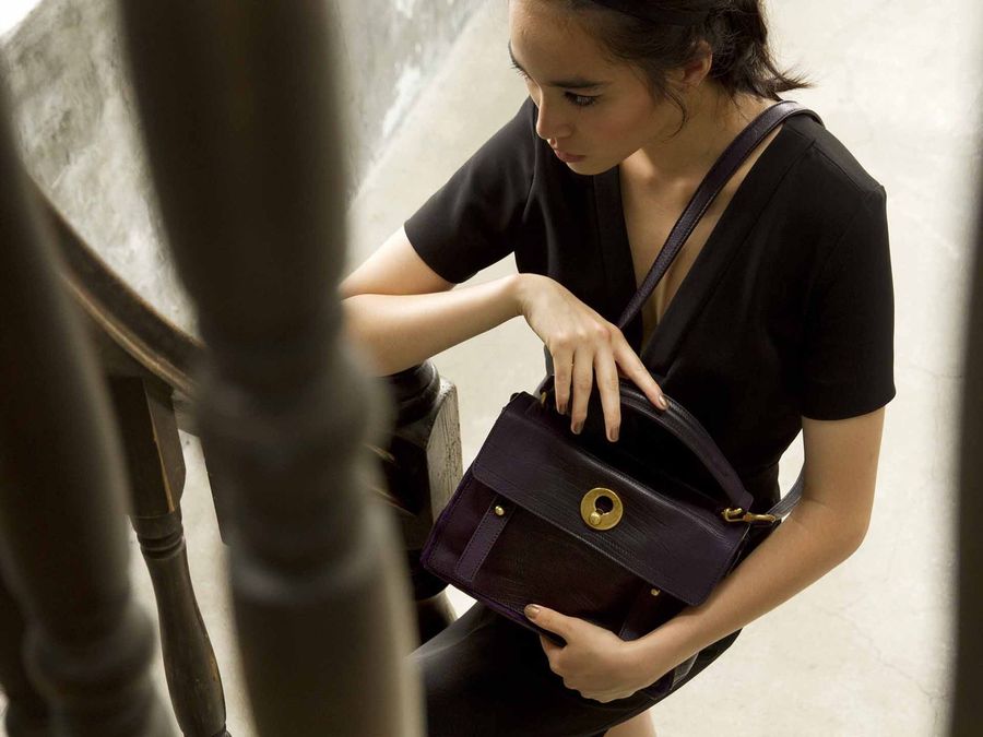 柱の陰でバッグを開ける女性