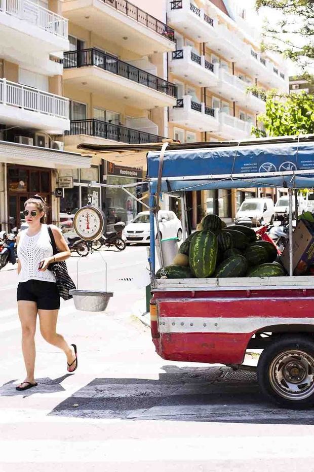 スイカを積んだ三輪トラックと、通りを歩く女性
