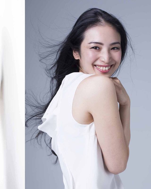 白いトップスで肩ごしに振り返る女性