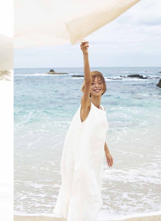海辺で白い布を掲げる女性
