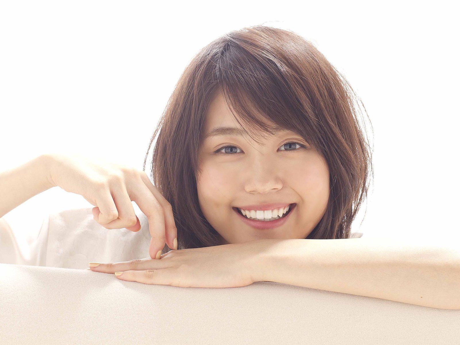 白い台に腕をのせて笑う女性