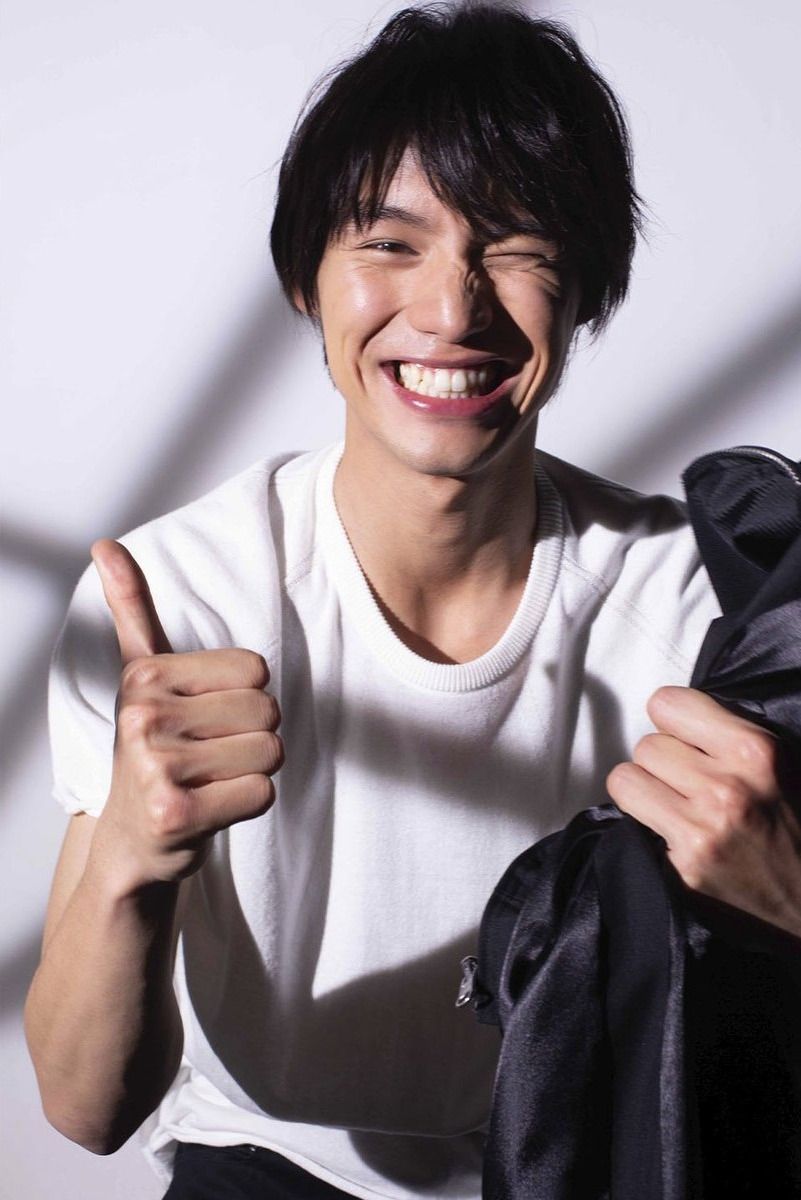 白いTシャツで親指を立てて笑う男性