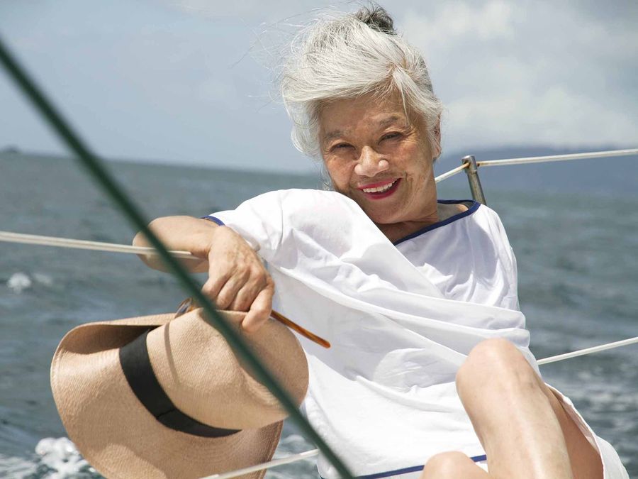 帆船で麦わら帽子を手にする白髪の女性