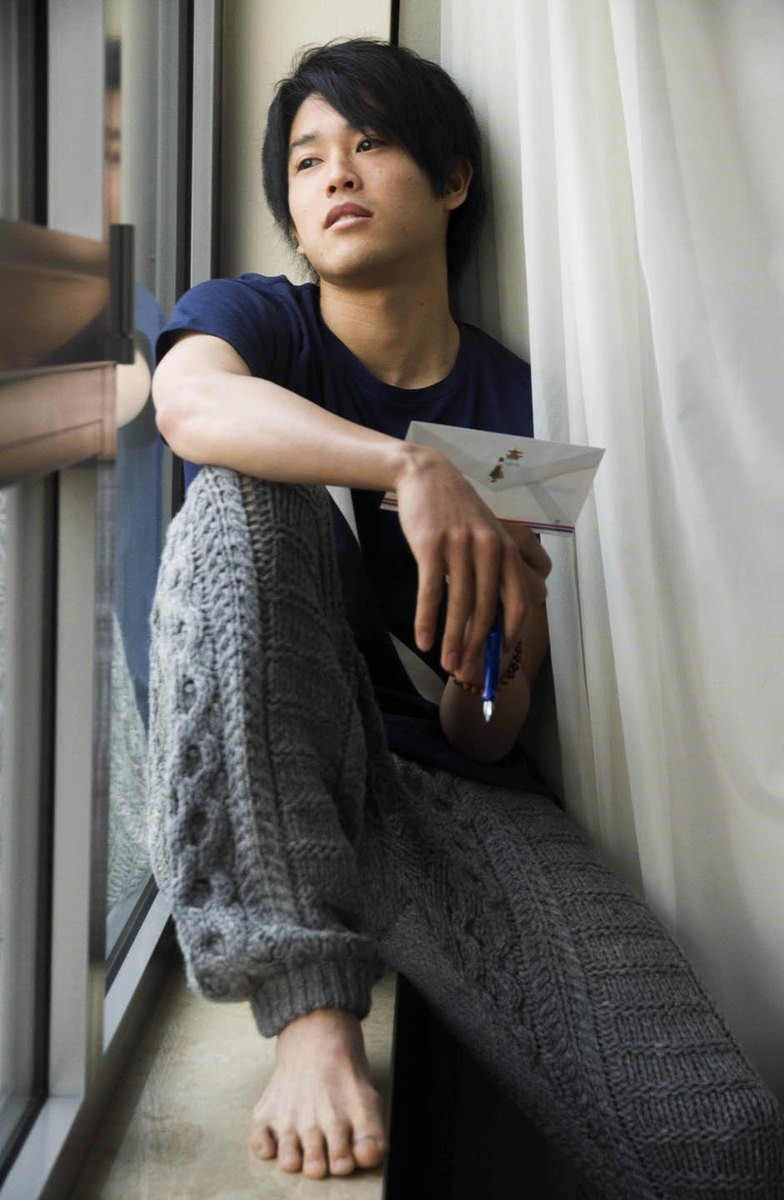 窓辺で膝を抱えて座る男性