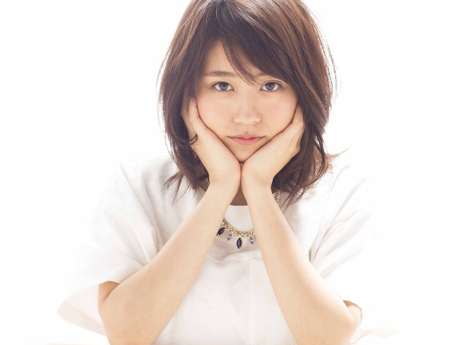白い服で両手に頬をあずける女性
