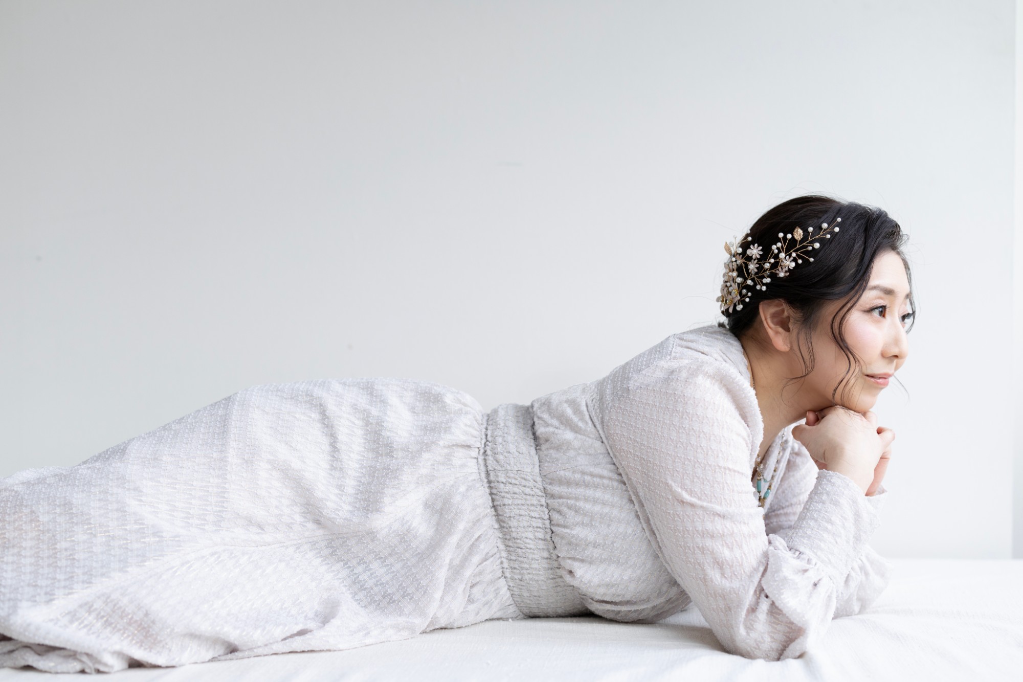 白いドレスで横たわり、遠くを見つめる女性
